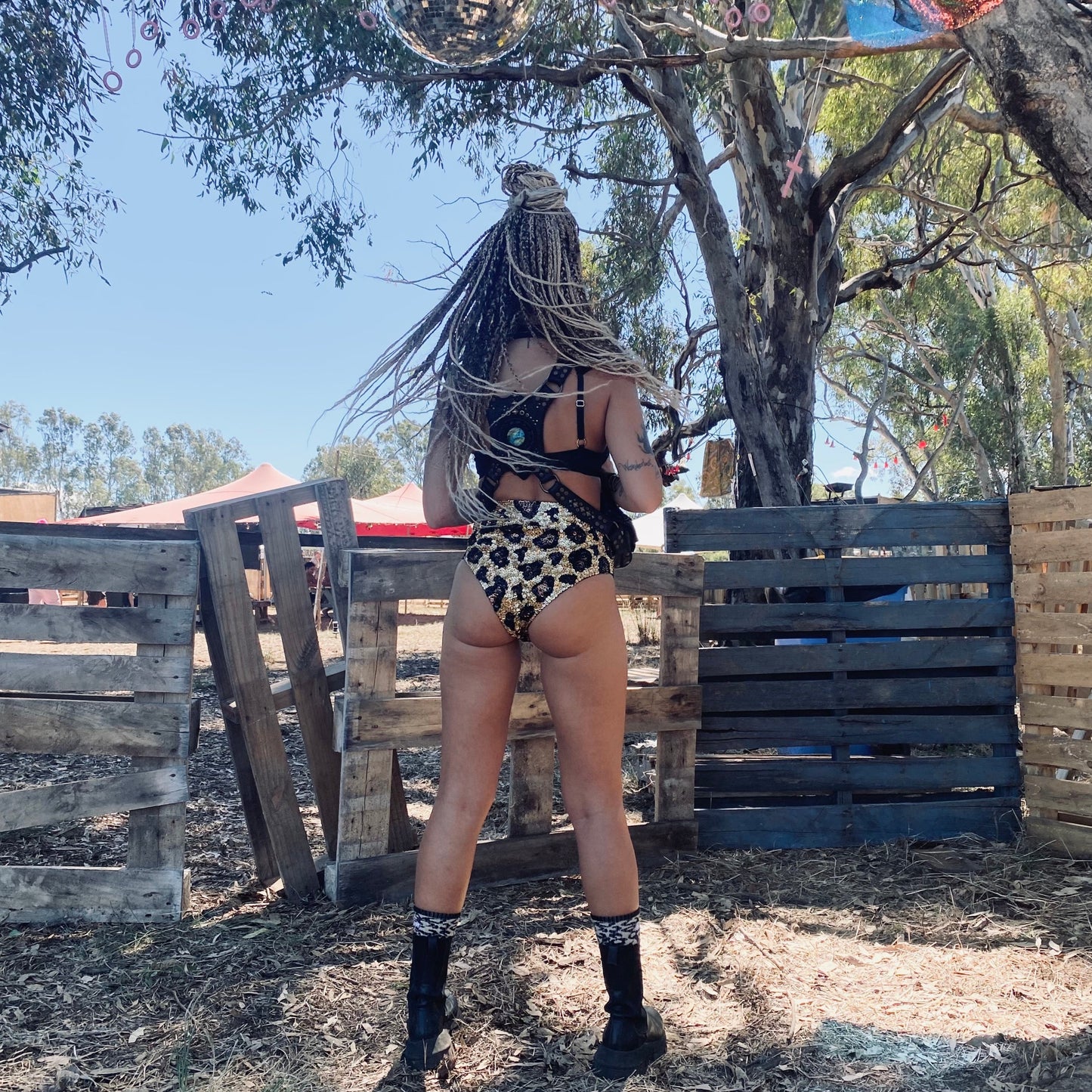 festival girl with booty shorts, hot pants, gold sequins, leopard sequins, leopard print hot pants, shorts, festival braids, festival hair, hairstyle, rave outfit, rave girl, festival model, festival fashion, body harness, bondage, festival boots.