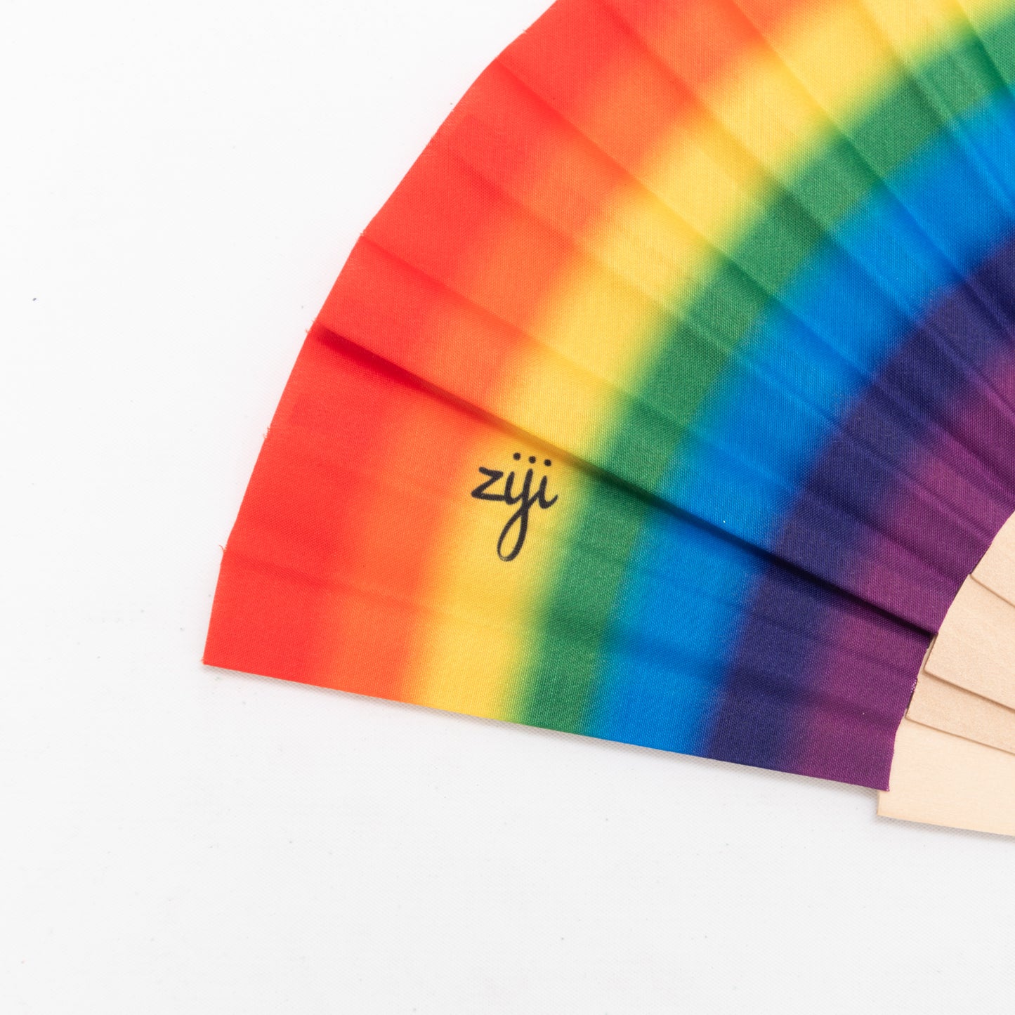 close up of large rave hand fan with rainbow design, made from fabric and wooden frame.