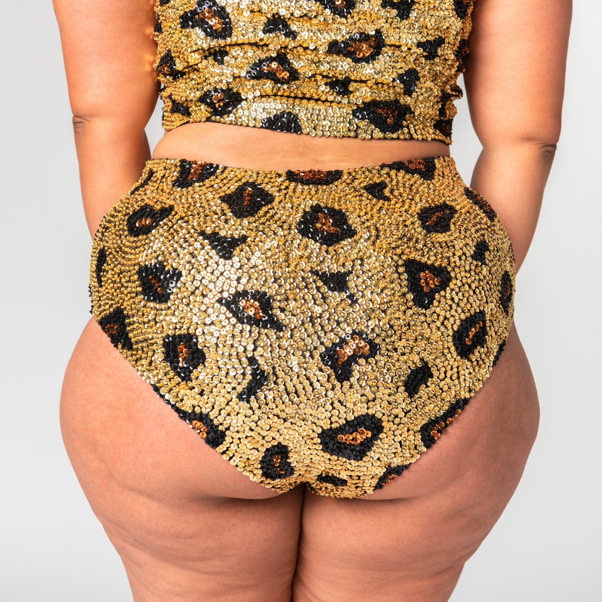 back view of high waist festival hot pants in gold leopard print design on plus size model.